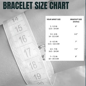K&ouml;nnte beinhalten: Ein wei&szlig;es Ma&szlig;band mit schwarzen Markierungen zeigt Zoll und Zentimeter. Die Tabelle zeigt Armbandgr&ouml;&szlig;en in Zoll basierend auf der Handgelenksgr&ouml;&szlig;e in Zoll und Zentimetern.