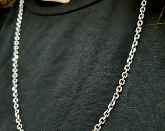 Könnte beinhalten: Eine silberne Kettenkette auf einem schwarzen Shirt.