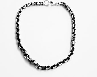 May include: A silver chain necklace with a box chain design. The chain is made of small, square links.