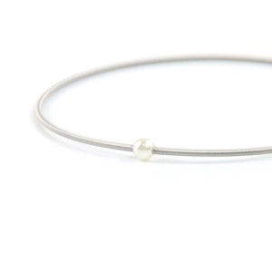 May include: A silver chain necklace with a single white pearl bead.
