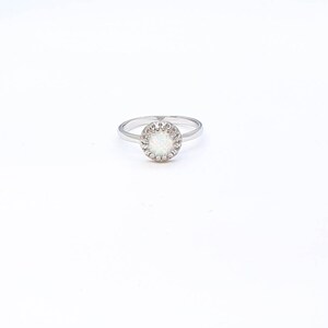 May include: A silver ring with a white opal stone set in a circle of small silver beads.