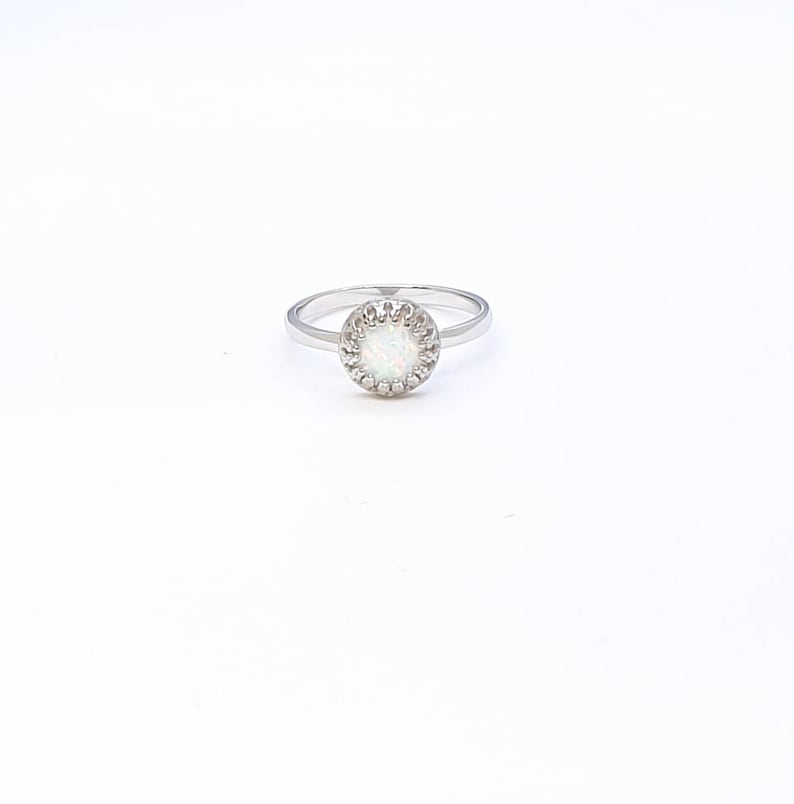 May include: A silver ring with a white opal stone set in a circle of small silver beads.