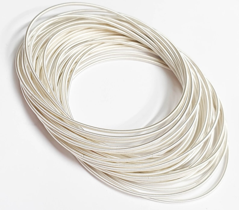 K&ouml;nnte beinhalten: Ein Stapel silberfarbener Metallringe, jeder Ring ist d&uuml;nn und rund. Die Ringe sind &uuml;bereinander gestapelt und bilden eine Spiralform.