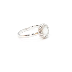 May include: A silver ring featuring a white opal stone set in a delicate filigree design.