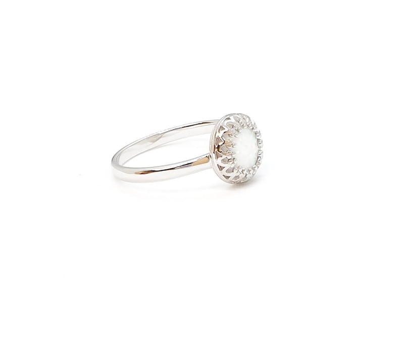 May include: A silver ring featuring a white opal stone set in a delicate filigree design.