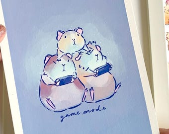 Puede incluir: Impresión enmarcada con cobayas jugando videojuegos, con la frase "game mode". Rodeada de pegatinas y tarjetas con ilustraciones de animales, todo en una paleta de colores pastel.