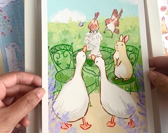 Può includere: Una stampa artistica incorniciata raffigurante una scena di giardino stravagante con due oche bianche, un coniglio e uccelli intorno a una statua. La stampa è in una cornice bianca, circondata da adesivi e biglietti con illustrazioni di animali.