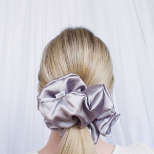 May include: A silver satin scrunchie with a white label that says "Made with Satin Silk".