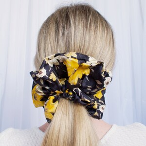 May include: A black and yellow floral patterned scrunchie for hair.
