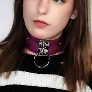 Puede incluir: Una mujer con el pelo largo y castaño que lleva un jersey de rayas blancas y negras con una gargantilla morada con un anillo plateado.