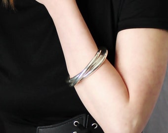 May include: A woman wearing a black t-shirt with a black corset belt. She is wearing a silver bracelet on her right wrist.