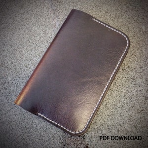 Puede incluir: Una cartera de cuero marrón con costuras blancas alrededor de los bordes.