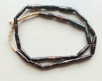May include: A necklace made of dark brown wooden beads with white stripes. The beads are strung on a natural twine cord.