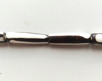 May include: Four black and white striped cylindrical beads strung together with gold spacers.