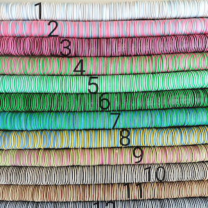 May include: Twelve rows of colorful wooden beads, each row a different pattern and color. The beads are stacked in a vertical line, with the first row being white, the second pink, the third red, the fourth green, the fifth light green, the sixth blue, the seventh yellow, the eighth brown, the ninth black and white, the tenth brown, the eleventh black and white, and the twelfth black.