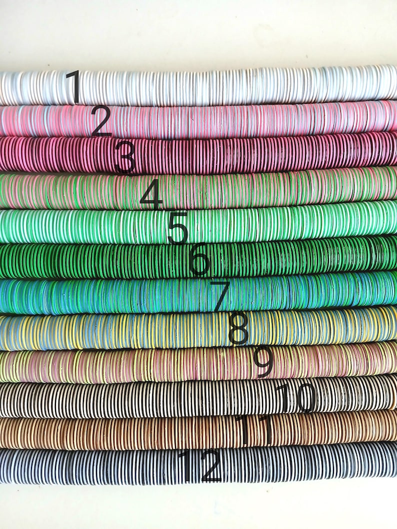 May include: Twelve rows of colorful wooden beads, each row a different pattern and color. The beads are stacked in a vertical line, with the first row being white, the second pink, the third red, the fourth green, the fifth light green, the sixth blue, the seventh yellow, the eighth brown, the ninth black and white, the tenth brown, the eleventh black and white, and the twelfth black.