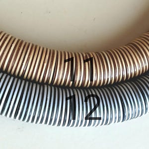 May include: Two woven hoops, one with brown and white stripes and the other with black and white stripes. The hoops are labeled with the numbers "11" and "12".
