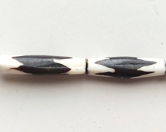 May include: Two brown and white cylindrical beads with a geometric pattern. The beads are made of bone or wood and are strung together.