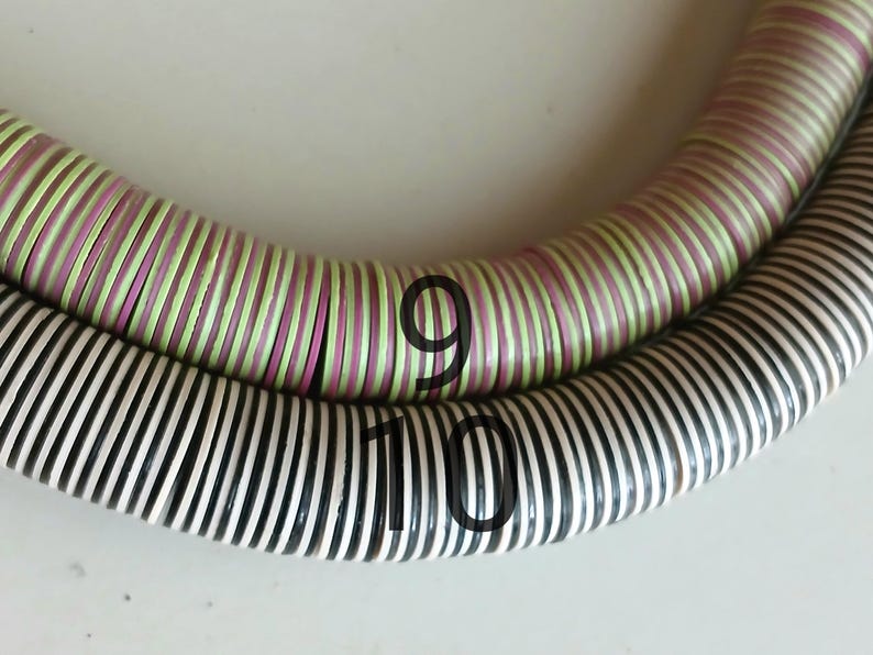May include: Two strands of colorful, striped, round beads. The top strand is light green and pink, and the bottom strand is black and white. The top strand has the number "9" written on it, and the bottom strand has the number "10" written on it.
