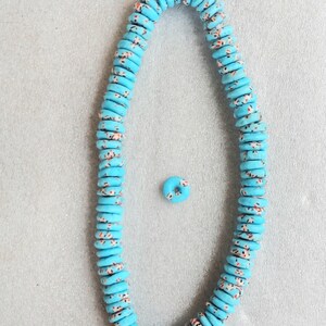 May include: A strand of turquoise-colored, flat, round beads with a speckled pattern of red and white. A single bead is separate from the strand. The beads are strung on a white cord, suitable for jewelry making or crafting.