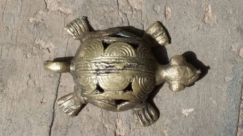 May include: A gold-colored metal turtle figurine with intricate details on its shell. The turtle is a popular symbol of good luck and longevity.