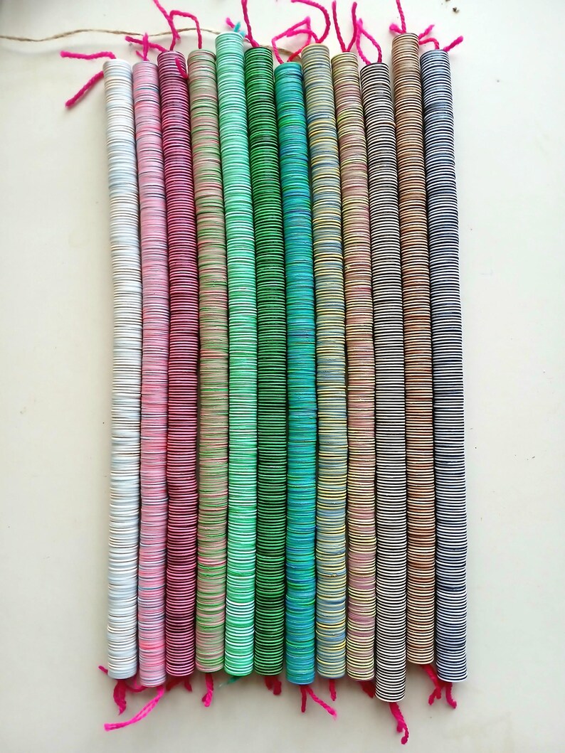 May include: A set of 14 colorful wooden bead strands, each strand is made of stacked round wooden beads with a different color pattern. The beads are stacked on a string and tied at the top with a pink string.