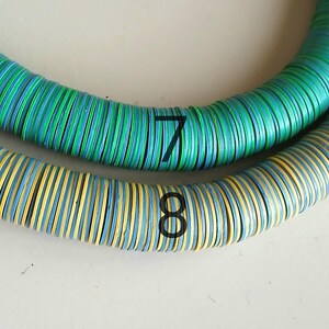 May include: Two strands of colorful, round, wooden beads. The top strand is green, blue, and white. The bottom strand is yellow, blue, and white. The strands are labeled with the numbers 7 and 8.