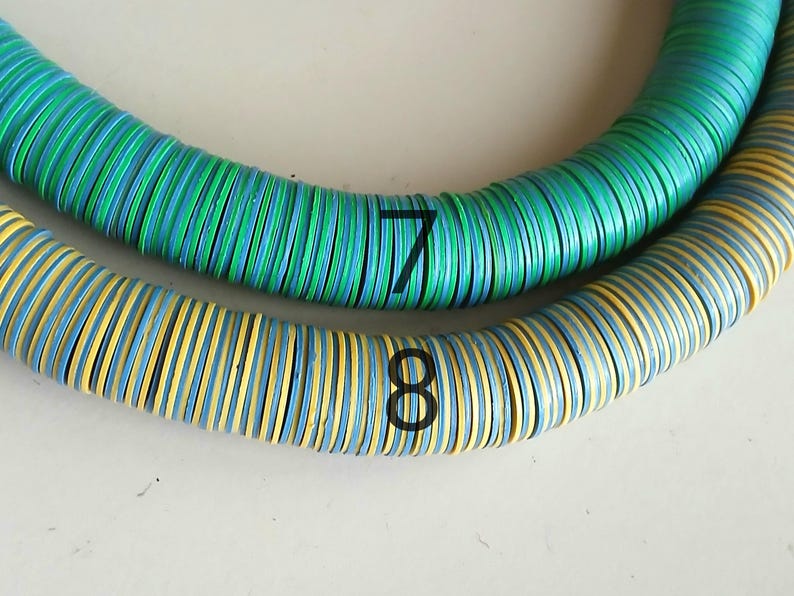 May include: Two strands of colorful, round, wooden beads. The top strand is green, blue, and white. The bottom strand is yellow, blue, and white. The strands are labeled with the numbers 7 and 8.