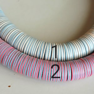 May include: Two strands of colorful round beads, one strand is white and blue, the other is pink and blue. The strands are labeled with the numbers 1 and 2.