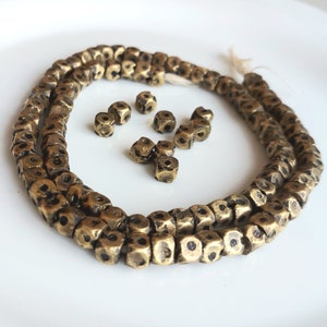 May include: A strand of brass beads with a textured, hammered finish. The beads are square shaped and have a dark patina. There are also loose beads in the image.