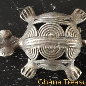 May include: A silver-colored turtle figurine with a detailed, intricate design on its shell. The turtle is a traditional symbol of longevity and good luck.