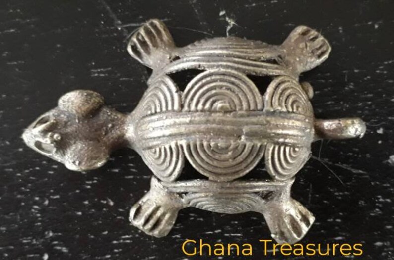 May include: A silver-colored turtle figurine with a detailed, intricate design on its shell. The turtle is a traditional symbol of longevity and good luck.