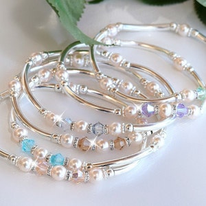 May include: A set of five silver bracelets with pearl and crystal accents. Each bracelet features a different colour crystal.