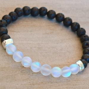 Peut inclure: Un bracelet composé de perles de lave noire et de perles blanches irisées. Le bracelet est doté d'entretoises en métal argenté entre les perles.