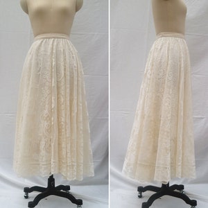 May include: A white lace skirt with a gathered waist and a full, flowing silhouette. The skirt is made of delicate lace with a floral pattern.