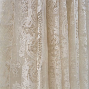May include: White lace fabric with a delicate floral pattern. The fabric is sheer and has a soft, flowing texture.