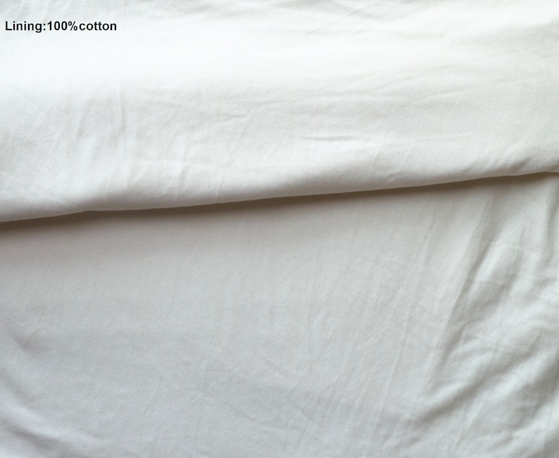 May include: Close-up of a white cotton fabric folded in half. The text "Lining: 100% cotton" is visible in the top left corner of the image.