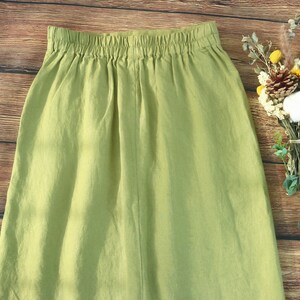 May include: A light green linen skirt with a wide elastic waistband. The skirt is a simple, casual style.