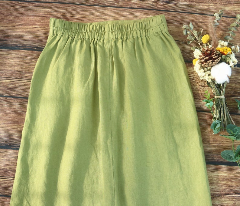 May include: A light green linen skirt with a wide elastic waistband. The skirt is a simple, casual style.