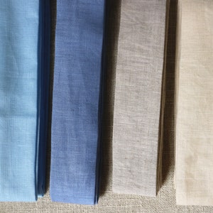 May include: Four fabric samples in different colors: light blue, dark blue, beige, and cream. The fabric is woven and has a linen texture.
