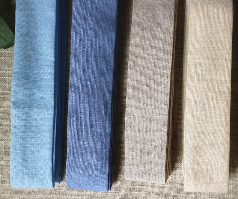 May include: Four fabric samples in different colors: light blue, dark blue, beige, and cream. The fabric is woven and has a linen texture.