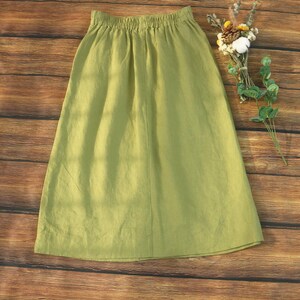 May include: A light green linen skirt with an elastic waistband. The skirt is knee-length and has a simple, casual style.