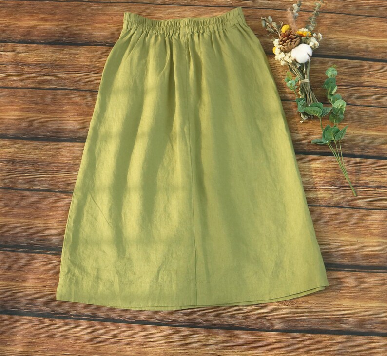 May include: A light green linen skirt with an elastic waistband. The skirt is knee-length and has a simple, casual style.