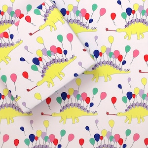 May include: White wrapping paper with a repeating pattern of yellow dinosaurs with colourful balloons on their backs. The dinosaurs are blowing party horns.