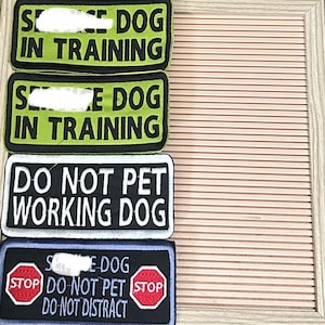 May include: Four embroidered patches with text for service dogs. Two green and black patches read "SERVICE DOG IN TRAINING." A black and white patch says "DO NOT PET WORKING DOG." A blue patch reads "SERVICE DOG, DO NOT PET, DO NOT DISTRACT."