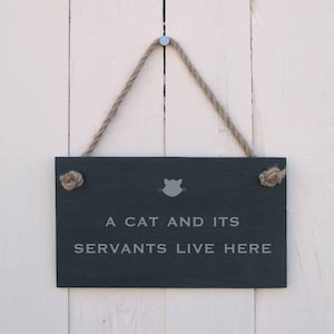 Hängande skylt 'En katt och dess tjänare bor här'