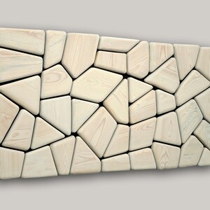 May include: A wall art piece made of light wood, with a geometric pattern of irregular shapes. The wood is a light beige color and the shapes are arranged in a random pattern.