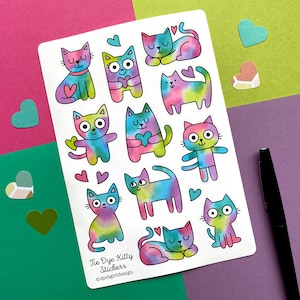 May include: A sheet of tie-dye kitty stickers with various cat poses and heart accents. The stickers feature a watercolor effect in vibrant colors like pink, blue, green, and yellow. The text "Tie Dye Kitty Stickers" and the designer's name are printed on the sheet.