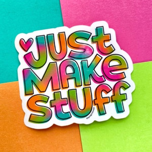 May include: A colorful sticker with the text "Just Make Stuff" in a rainbow gradient. The sticker has a white border and a small heart in the upper left corner.