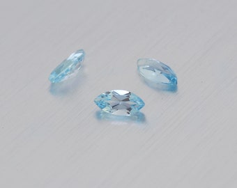 May include: Three light blue marquise-shaped gemstones on a white background.